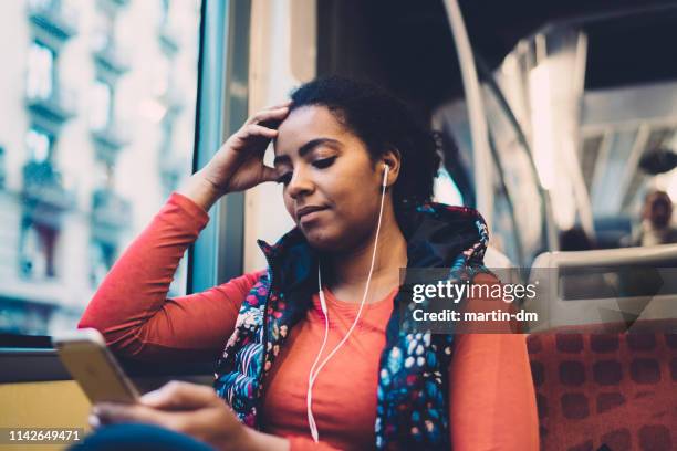 mixed race vrouw in de bus te luisteren naar muziek - sad commuter stockfoto's en -beelden