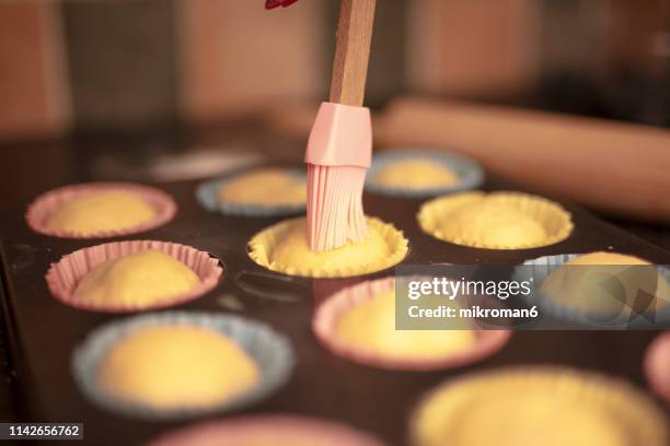adding the last glaze on home made cupcakes before backing them - muffin tin stock pictures, royalty-free photos & images