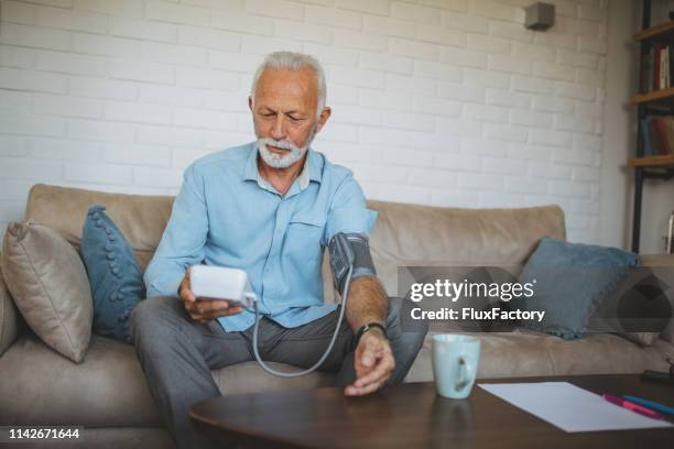 seniorenmensch misst seinen blutdruck - blood pressure stock-fotos und bilder