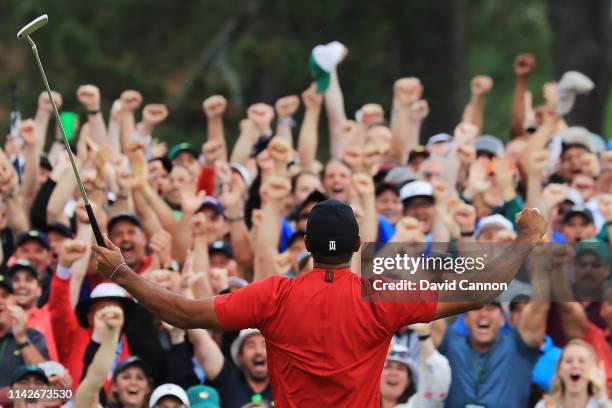Patrons cheer as Tiger Woods of the United States celebrates after sinking his putt on the 18th green to win during the final round of the Masters at...