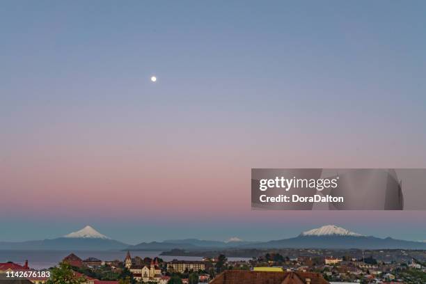 osorno volcano, volcán calbuco and moon at dusk panoramic in chilean lake district - puerto varas, chile - llanquihue lake stock pictures, royalty-free photos & images