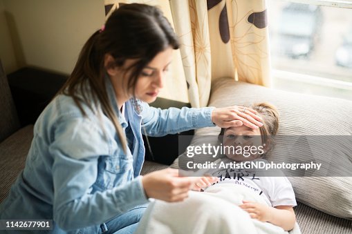 Mother checking on sick daughter laying in bed Mother checking on sick daughter laying in bed
