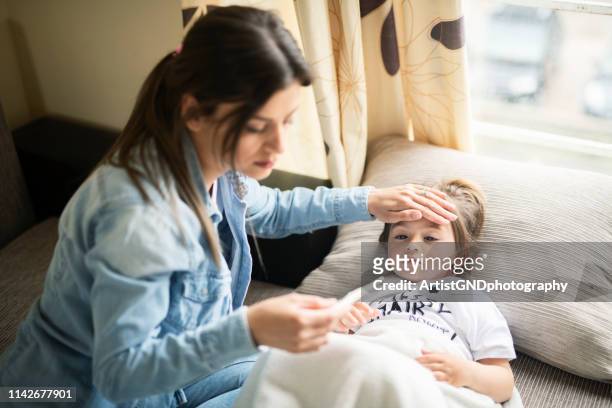 mother checking on sick daughter laying in bed - family with one child stock pictures, royalty-free photos & images