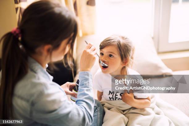 mother giving daughter medicine - family with one child stock pictures, royalty-free photos & images