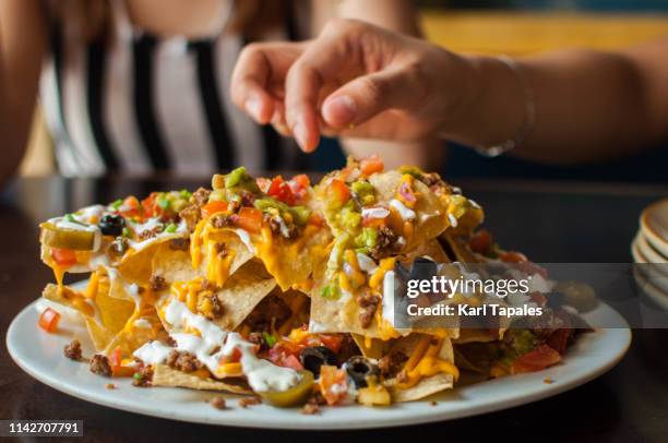 a young woman is eating a freshly made tacos - mexicaanse-gerechten stockfoto's en -beelden