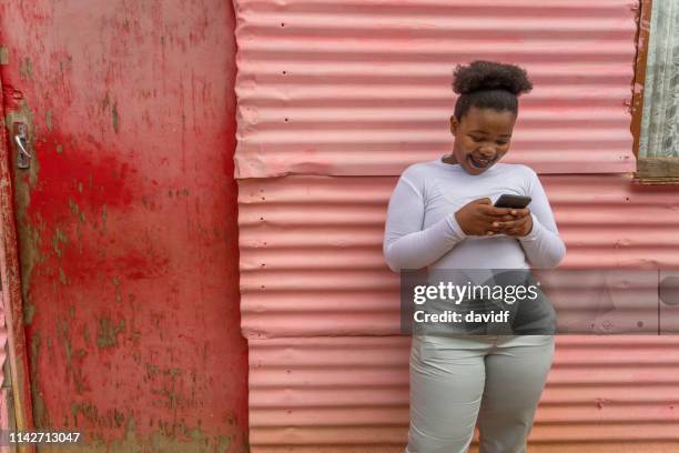 mulher africana feliz nova que usa um telefone móvel - township - fotografias e filmes do acervo