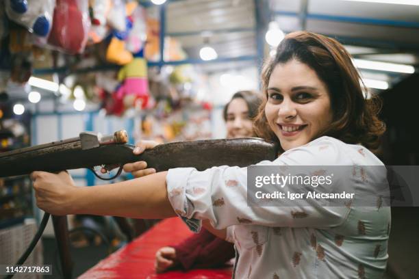 woman shooting with shotgun at amusement park - air rifle shooting stock pictures, royalty-free photos & images