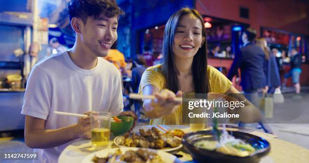 young couple enjoying street food - hong kong street food stock pictures, royalty-free photos & images