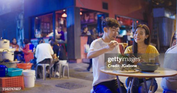 young couple enjoying street food - chinese street food stock pictures, royalty-free photos & images