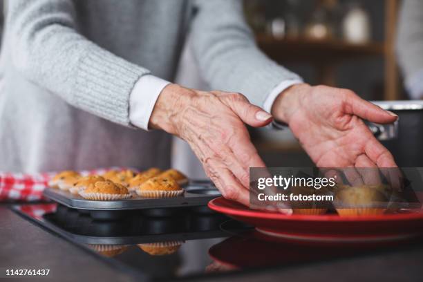 menschliche hände beschlummen muffins - food plating stock-fotos und bilder