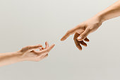 Two male hands trying to touch isolated on grey studio background