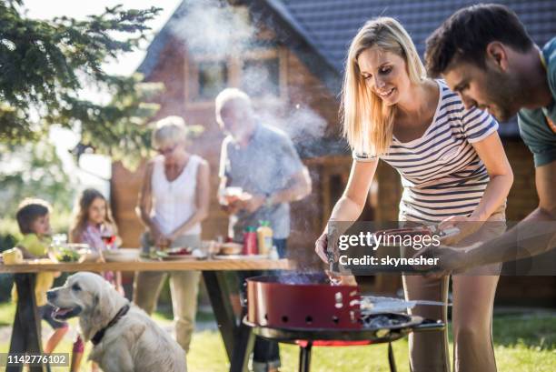 happy extended family preparing barbecue in the backyard. - extended family outdoors spring stock pictures, royalty-free photos & images