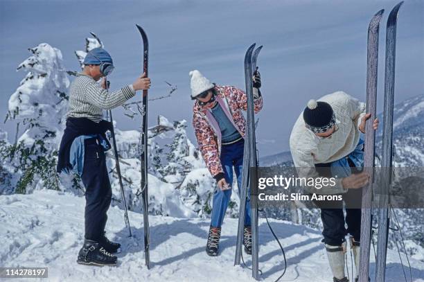 Three skiers inspecting their skis on the slopes of the Sugarbush Mountain ski resort in Warren, Vermont, USA, circa 1960. The Sugarbush resort is...