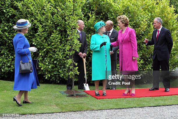 Queen Elizabeth II speaks with President Mary Mc Aleese after planting a tree at ceremony in Aras An Uachtarain while on the first day of her State...