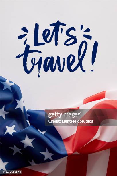 top view of united states of america flag and lets travel lettering on white surface