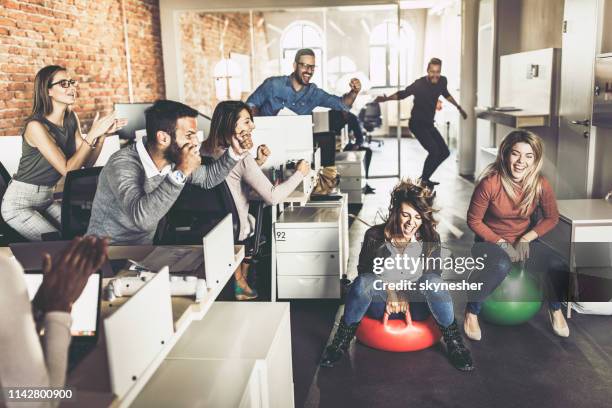 joyful business colleagues having fun in space hopper challenge at casual office. - hoppity horse stock pictures, royalty-free photos & images