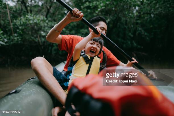 father teaching child how to paddle kayak in mangrove swamp, japan - deporte acuático fotografías e imágenes de stock