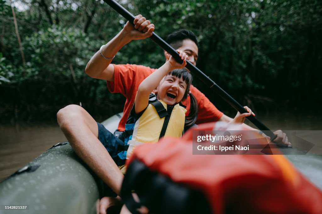 Father teaching child how to paddle kayak in mangrove swamp, Japan