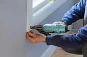 Carpenter using air nail gun to moldings for window, close up on nail gun