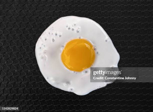 close up of fried egg on non sticky pan - egg yolk stock pictures, royalty-free photos & images