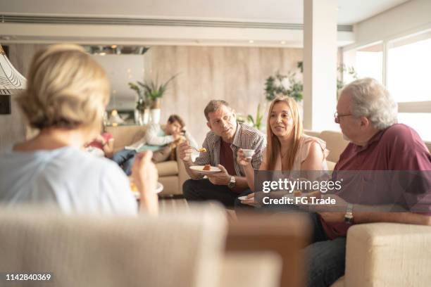 familie bei kaffee und kuchen zusammen im wohnzimmer - friends talking living room stock-fotos und bilder