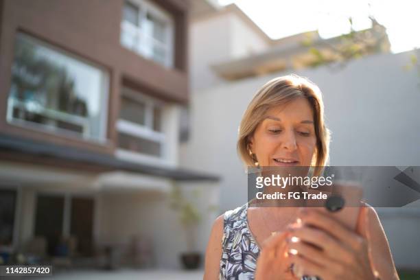 mature woman in front of a house using mobile - 63 building stock pictures, royalty-free photos & images