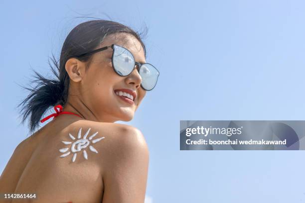 suntan lotion woman with sunscreen solar cream over sky background - beautiful women spreading stock-fotos und bilder