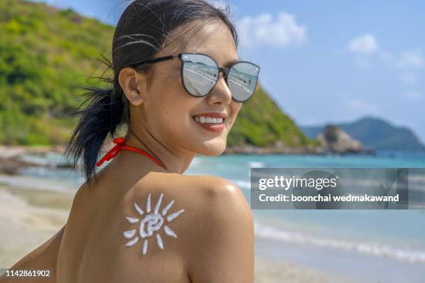 suntan lotion woman with sunscreen solar cream over sky background - beautiful women spreading stock-fotos und bilder