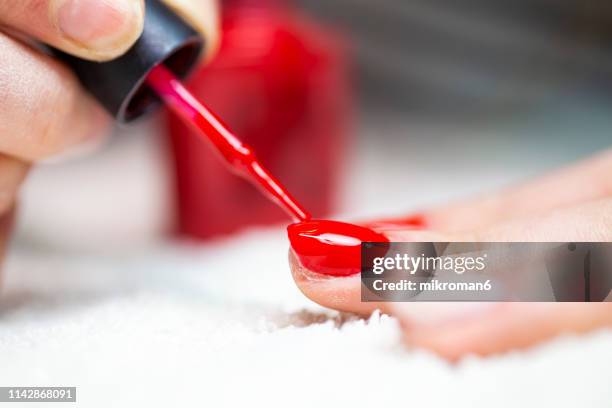 nail technician painting clients nails bright red colour - gel effect stock pictures, royalty-free photos & images