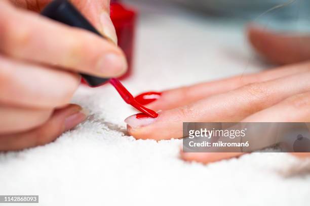 nail technician painting clients nails bright red colour - gel effect stock pictures, royalty-free photos & images