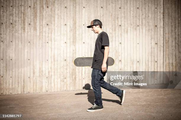 caucasian man carrying skateboard near wooden wall - swaying stock pictures, royalty-free photos & images