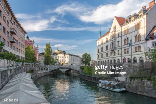 buildings and pedestrian bridge over urban canal, ljubljana, central slovenia, slovenia - lubiana stock pictures, royalty-free photos & images