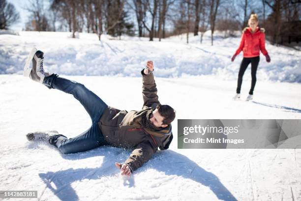 caucasian man falling while ice skating on frozen lake - アイススケート ストックフォトと画像