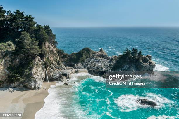 aerial view of waves washing up on rocky beach - central coast stock pictures, royalty-free photos & images