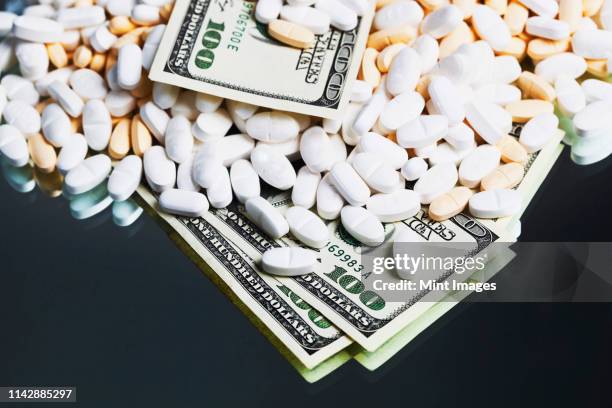 prescription medication and one hundred dollar bills - prescription drug costs stock pictures, royalty-free photos & images