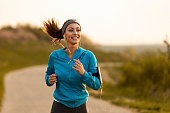 Happy female runner jogging in the morning in nature.