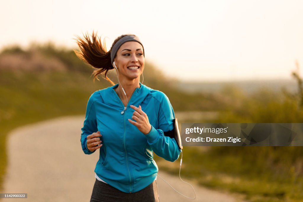 Happy female runner jogging in the morning in nature.