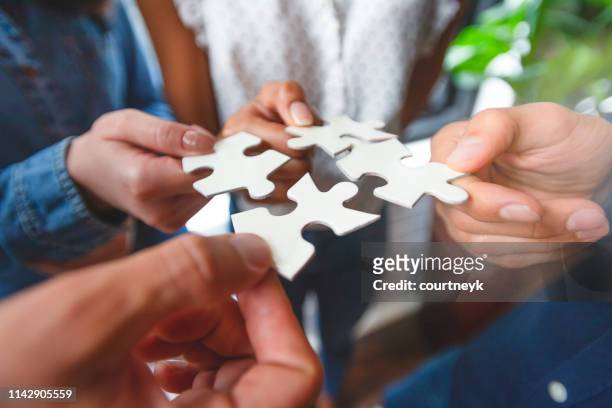 group of business people holding a jigsaw puzzle pieces. - sharing stock pictures, royalty-free photos & images