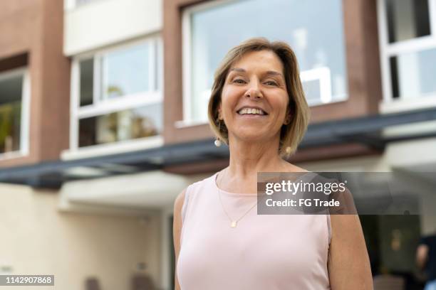 portrait of senior woman in front of new house - person in front of house stock pictures, royalty-free photos & images