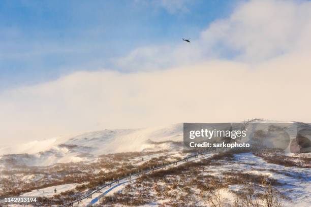 winter kletterleitung mit hubschrauber im hintergrund - arctic oil stock-fotos und bilder