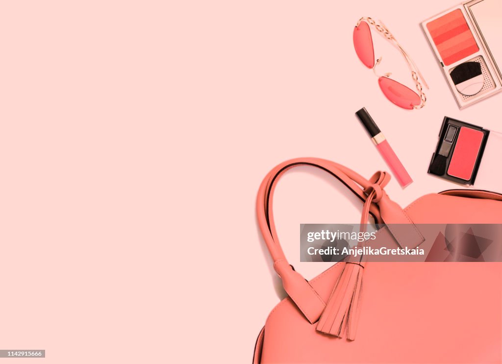 Woman's handbag, make-up and sunglasses in trend coral color of 2019