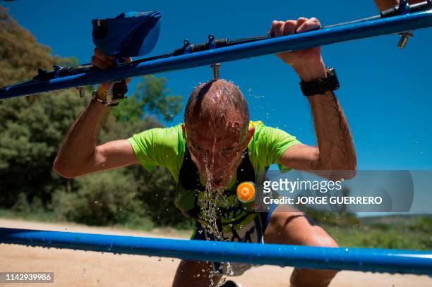 Runner pours water on himself during the XXII 101km international cross-country competition in Ronda on May 11, 2019. - About 8,500 participants,...
