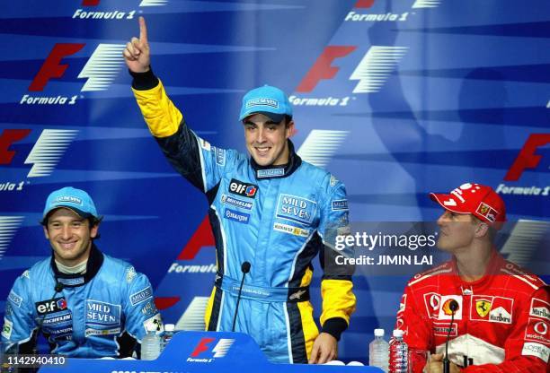 Renault driver Fernando Alonso of Spain raises his hand in celebrate becoming the youngest pole position winner while teammate Jarno Trulli of Italy...