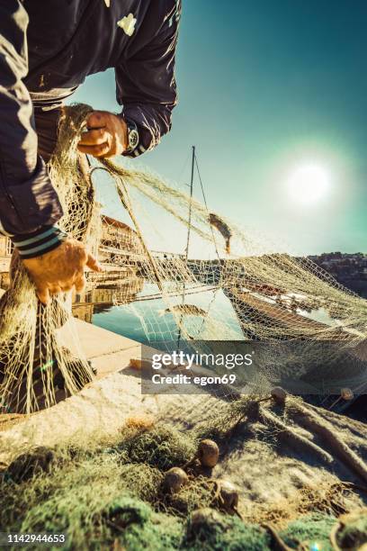 fisherman cleaning the fishnet - industrial fishing net stock pictures, royalty-free photos & images