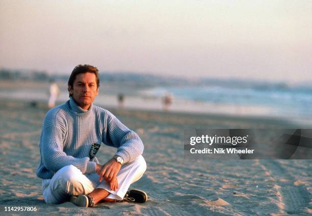 German actor Helmut Berger, sits on sandy beach in Santa Monica circa 1985: