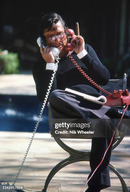 American movie producer Robert Evans sits poolside on two telephones in garden of his Beverly Hills home in california, circa 1978: