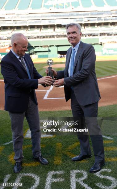 Sandy Alderson of the Oakland Athletics presents Executive Vice President of Baseball Operations Billy Beane with his Executive of the Year Award...