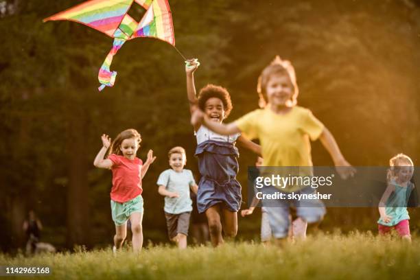 bambini felici che giocano con l'aquilone in primavera al parco. - giochi per bambini foto e immagini stock