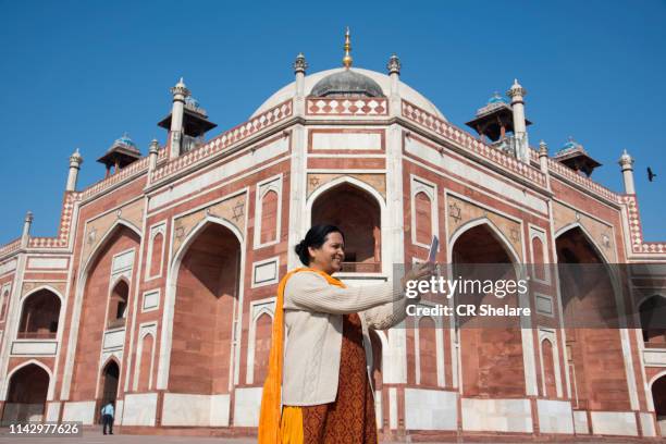 indian woman taking selfie with smartphone in front of humayun's tomb, delhi, india, unesco world heritage site. - the cemetery for foreigners stock pictures, royalty-free photos & images