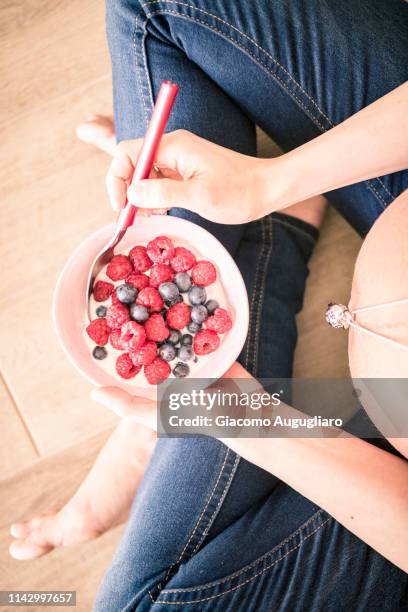 close up of a pregnant woman holding a bowl full of berries. italy - schneidersitz stock-fotos und bilder